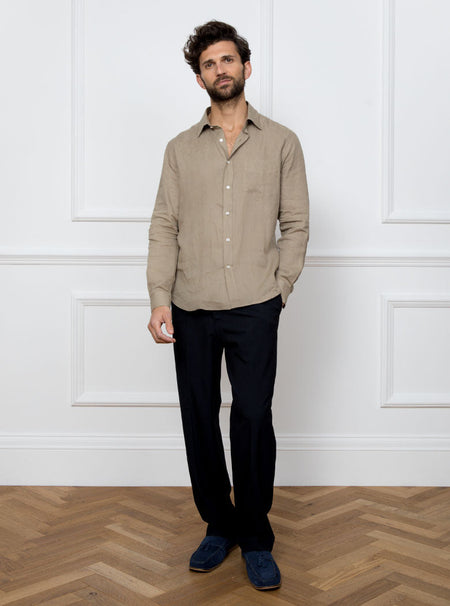 Man wearing a tan long sleeved shirt with pocket detail made with 100% linen in a Thomas Mason fabric.